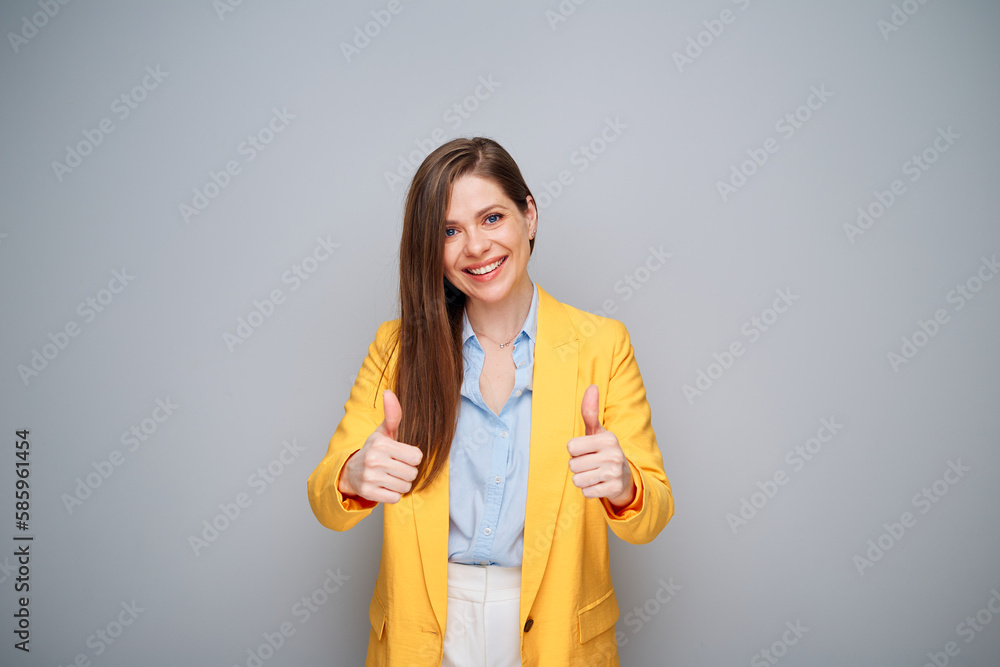 Smiling woman in yellow jacket on gray background showing thumbs up. Smiling woman in yellow jacket on gray background showing thumbs up.
