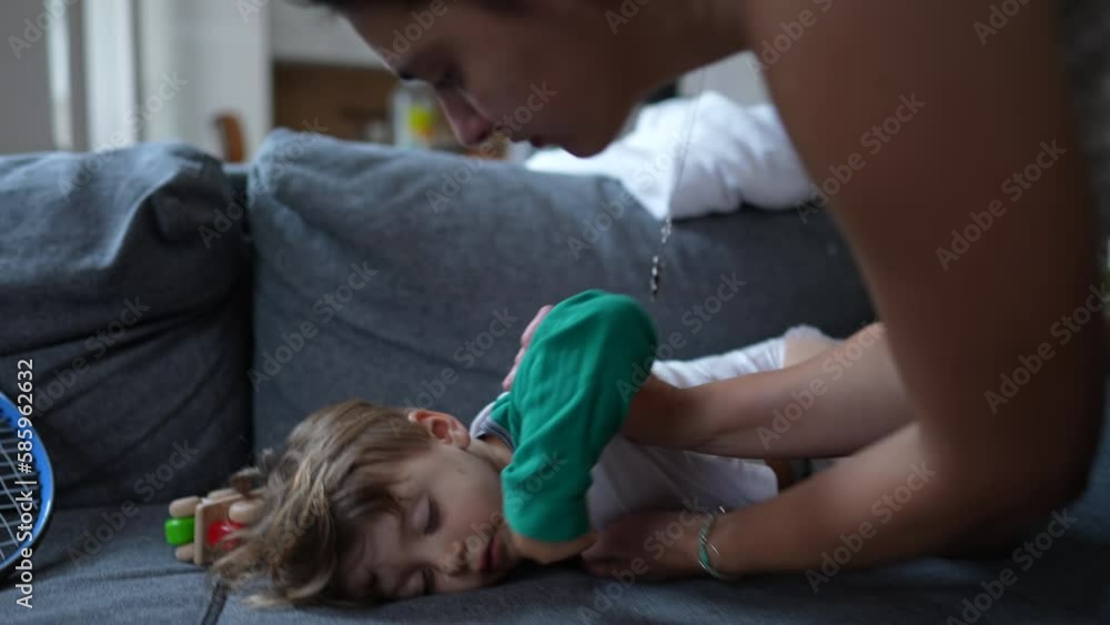 Mother carrying sleeping child into bed. Small boy asleep on couch. Parent putting toddler to sleep Mother carrying sleeping child into bed. Small boy asleep on couch. Parent putting toddler to sleep
