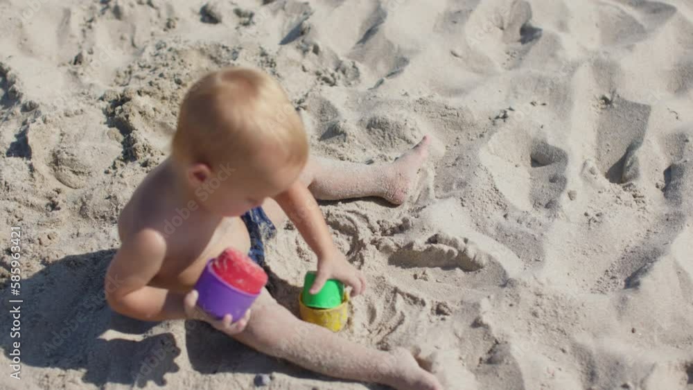 little toddler boy sitting white sandy beach playing colorful plastic molds learning forms and sizes. happy family summer vacations. seaside activity child kid educational games nature. motor skills little toddler boy sitting white sandy beach playing colorful plastic molds learning forms and sizes. happy family summer vacations. seaside activity child kid educational games nature. motor skills