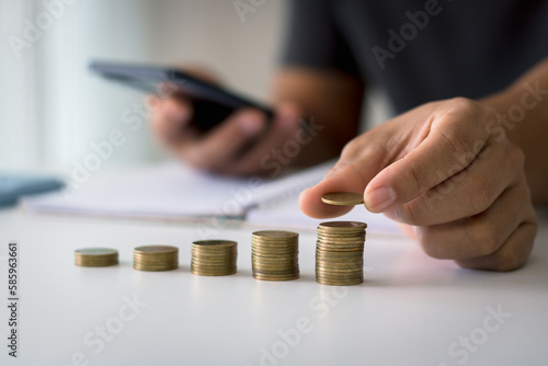 Businessman saving money concept financial. hand holding coins putting on stack using smartphone and calculator to calculate. concept of saving money for finance accounting.
