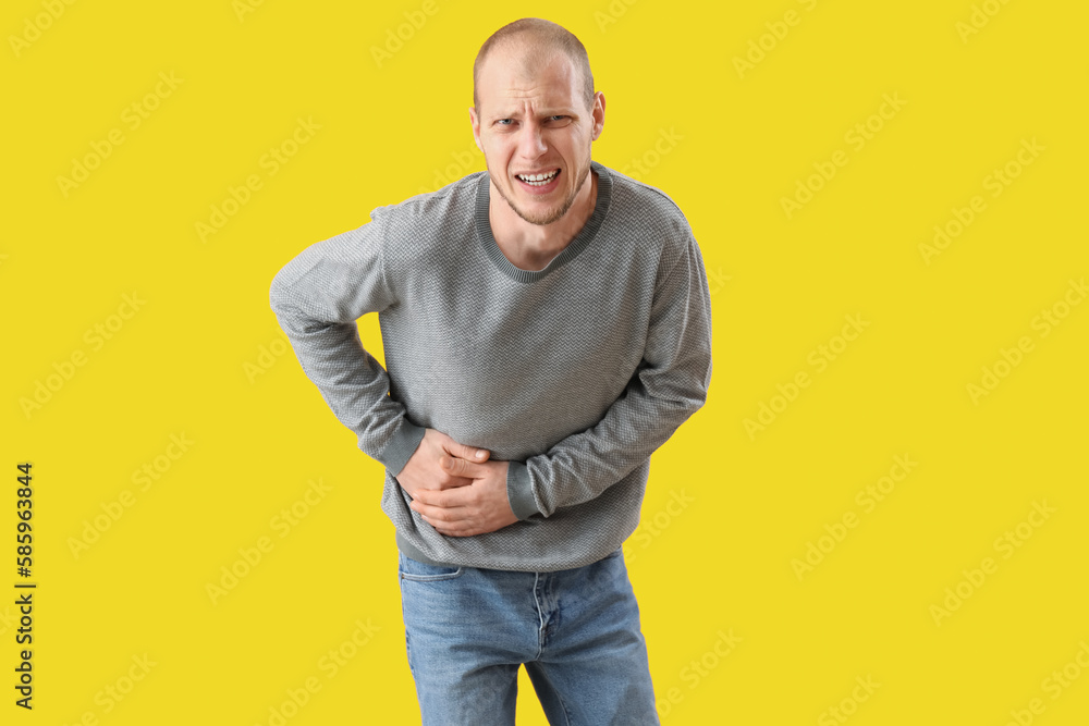 Young man with appendicitis on yellow background Young man with appendicitis on yellow background