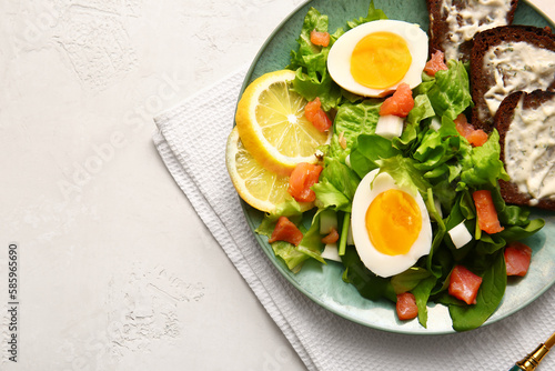Plate of delicious salad with boiled eggs and salmon on white background