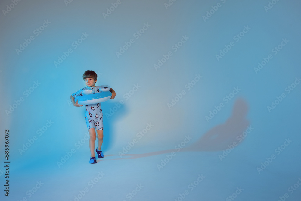 Happy cute boy 6 years old with a life buoy at the blue background Happy cute boy 6 years old with a life buoy at the blue background