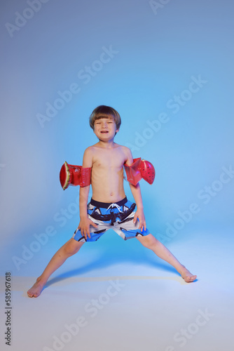 Happy cute boy 6 years old with a life buoy at the blue background