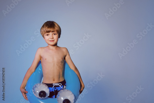 Happy cute boy 6 years old with a life buoy at the blue background