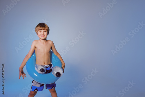Happy cute boy 6 years old with a life buoy at the blue background