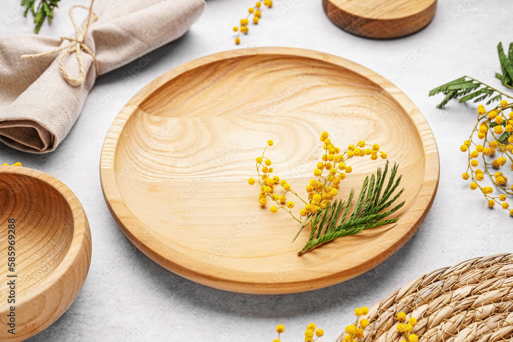 Composition with clean wooden dishes, napkin and mimosa flowers on white grunge table Composition with clean wooden dishes, napkin and mimosa flowers on white grunge table
