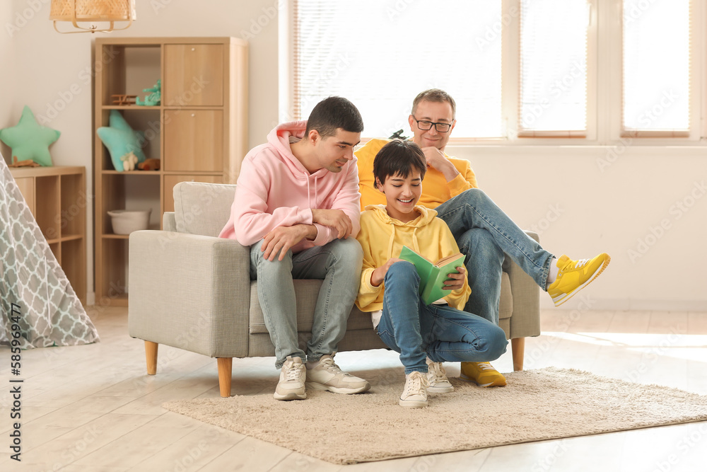 Happy little boy with his dad and grandfather reading book at home Happy little boy with his dad and grandfather reading book at home