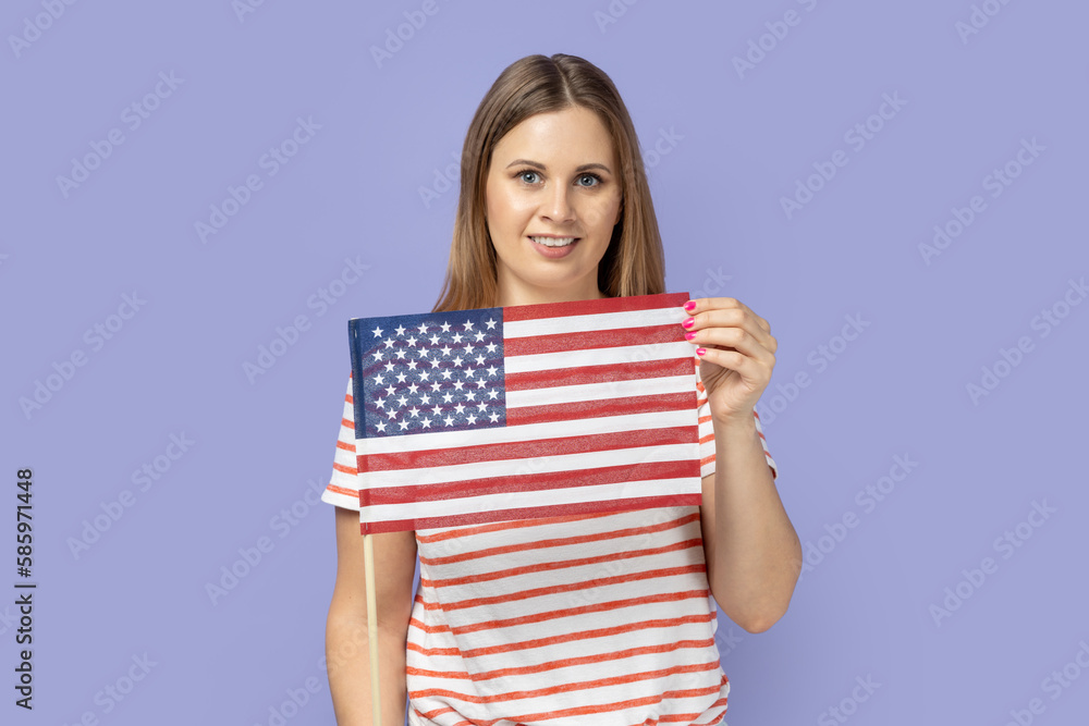 Woman holding flag of united states of america, celebrating independence day, having calm expression Woman holding flag of united states of america, celebrating independence day, having calm expression