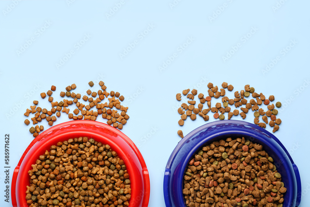 Bowls of dry pet food on color background