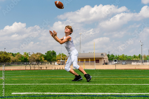 Youth preteen boy football player in uniform with football on football field