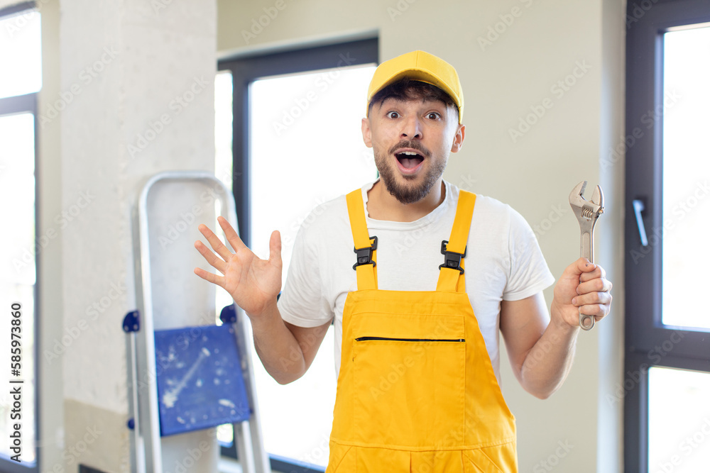 young handsome man feeling happy and astonished at something unbelievable. handyman concept young handsome man feeling happy and astonished at something unbelievable. handyman concept