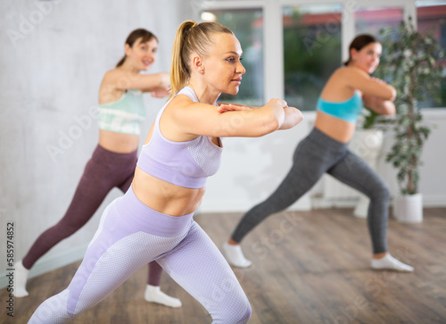 Cheerful sporty young woman practicing energetic dance moves with group in choreography class ..