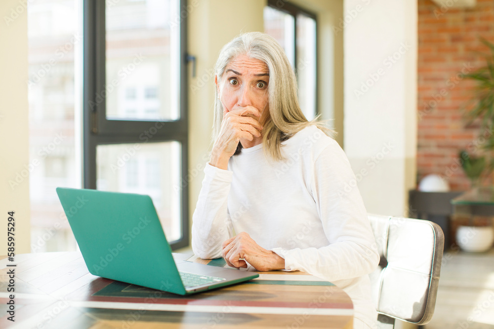 senior pretty woman covering mouth with a hand and shocked or surprised expression with a laptop senior pretty woman covering mouth with a hand and shocked or surprised expression with a laptop