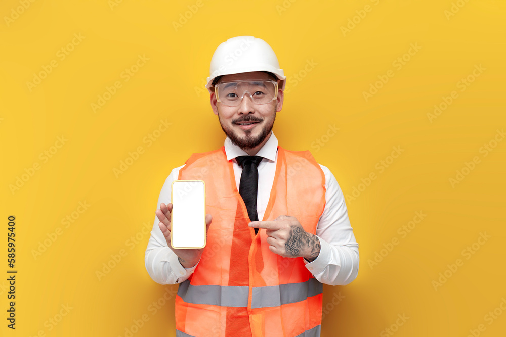 asian foreman in uniform showing blank smartphone screen on yellow isolated background, korean civil engineer asian foreman in uniform showing blank smartphone screen on yellow isolated background, korean civil engineer
