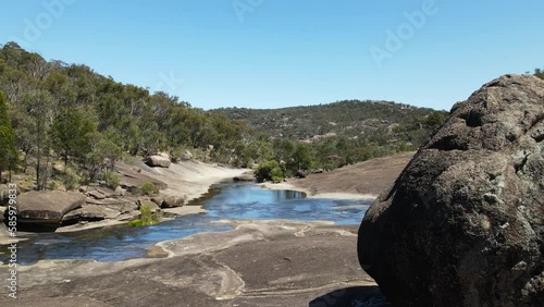 Dramatic landscape of balancing boulders along a flowing creek bed carved through the rugged Australian bushland. photo