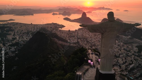 Rio de Janeiro, Brazil - March 21, 2023: Christ the Redeemer statue on top of the Corcovado Mountain with the Sugarloaf Mountain in the  horizon on sunrise.