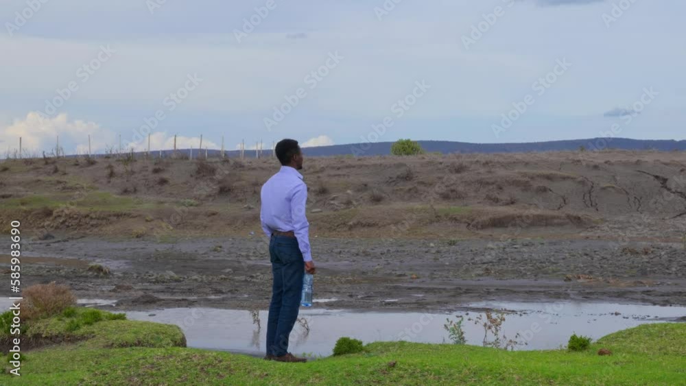 Person Holding Bottle Of Water Standing Out In Nature Looking Around Person Holding Bottle Of Water Standing Out In Nature Looking Around