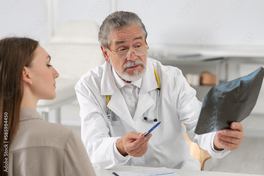 Orthopedist showing X-ray picture to patient in clinic Orthopedist showing X-ray picture to patient in clinic