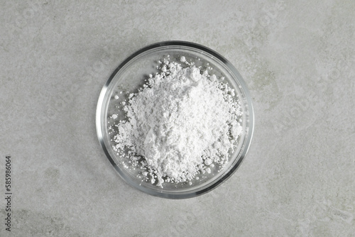 Petri dish with calcium carbonate powder on light grey table, top view