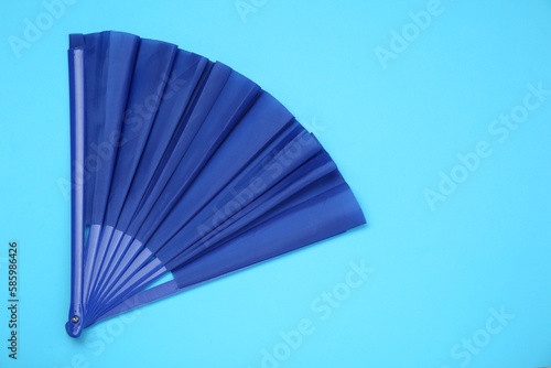 Bright color hand fan on light blue background  top view. Space for text