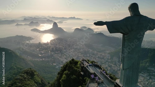 Rio de Janeiro, Brazil - March 21, 2023: Christ the Redeemer statue on top of the Corcovado Mountain with the Sugarloaf Mountain in the  horizon on sunrise. photo