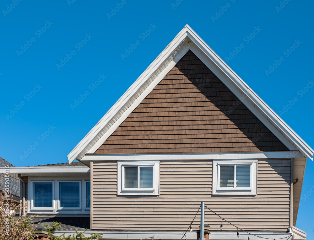 Top of a house with nice windows in the blue sky background. Beautiful Home Exterior. Real Estate Exterior Front House