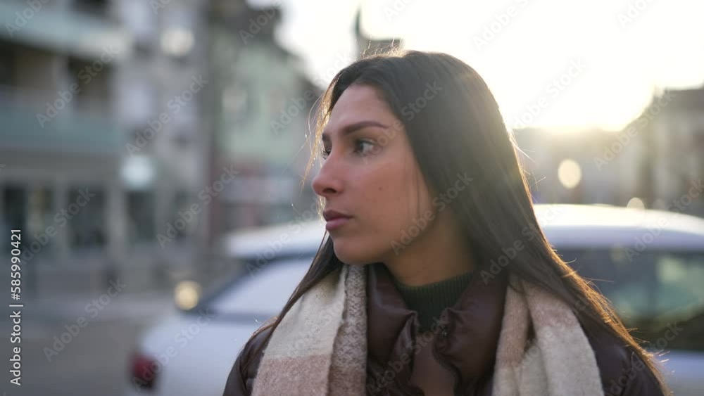 One young thoughtful Middle Eastern woman standing in city street outside during sunset time. Serious Arab adult girl in 20s One young thoughtful Middle Eastern woman standing in city street outside during sunset time. Serious Arab adult girl in 20s