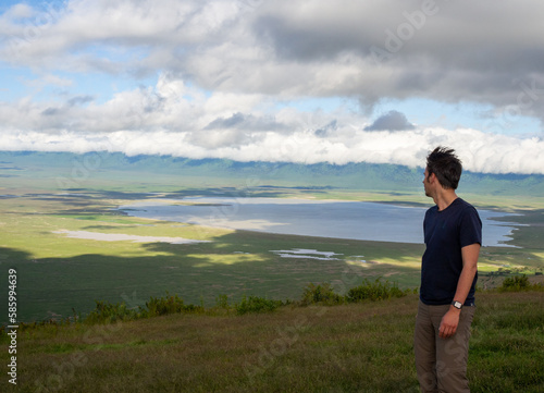 Young caucasian man standing on top of a green hill and enjoying the view in Serengeti National Park