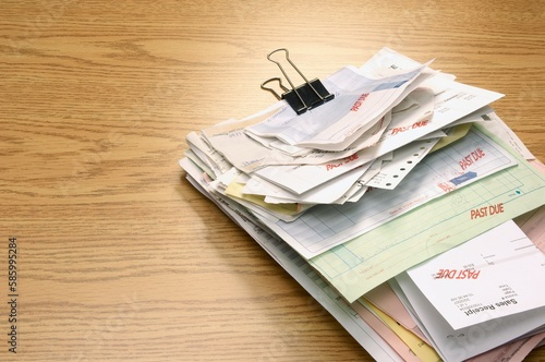 Close-up shot of a clip board with many late being paid bills