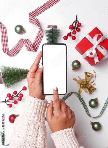 Vertical shot of a female hands touching the smartphone screen over the Christmas decorations