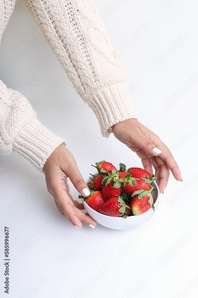 Vertical shot of woman's hands holding a bowl of strawberries on a white background. Vertical shot of woman's hands holding a bowl of strawberries on a white background.