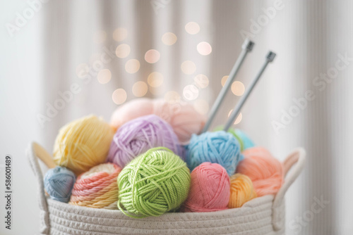Cozy homely atmosphere. Female hobby knitting. Yarn pastel multicolor in a basket. Skeins, balls, knitting needles, hooks and scissors.