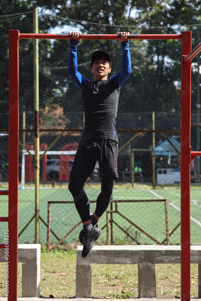 Fototapeta premium Muscular built young athlete working out at outdoor gym