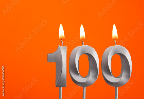 Number 100 - Silver Anniversary candle on orange background