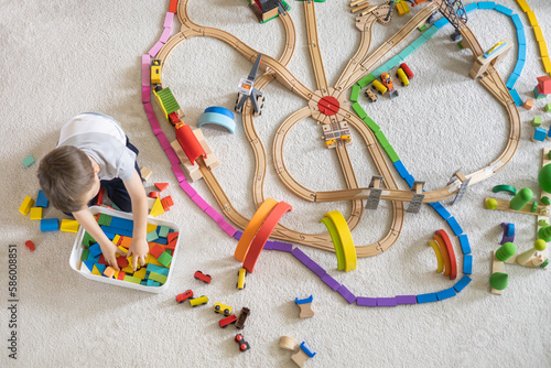Fotografie, Obraz Preschool baby boy playing wooden Montessori materials rainbow arch railways at childish room