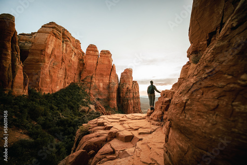 Horizontal wide angle view of woman standing at sunset from Cathedral Rock in Sedona.