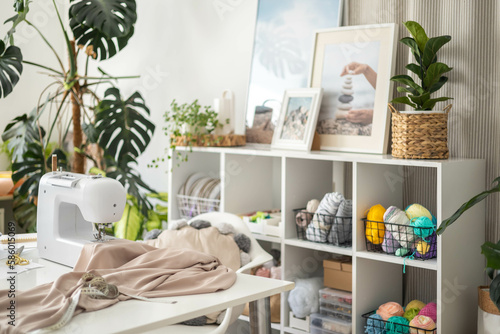 Modern workplace of tailor textile craft designer table with sewing machine and laptop near window
