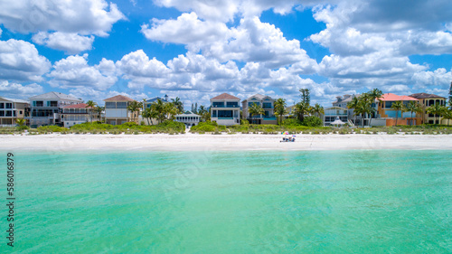 Calm Water Level View of Homes on a Beach in Naples  Florida with Foliage on the Coast and a Blue Sky Featuring Puffy White Clouds