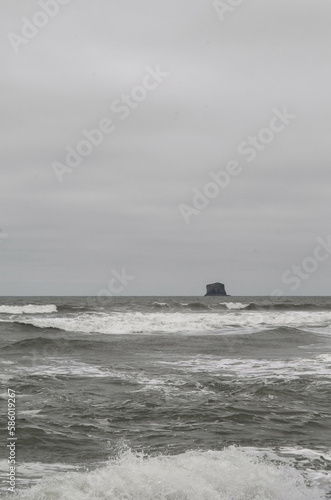 Lonely island in dark gloomy beach with choppy waves monochromatic