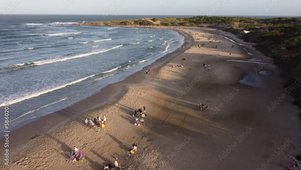 Aerial flyover Playa Grande Beach with resting people in Punta del Disable during sunset time - Uruguay,South America Aerial flyover Playa Grande Beach with resting people in Punta del Disable during sunset time - Uruguay,South America