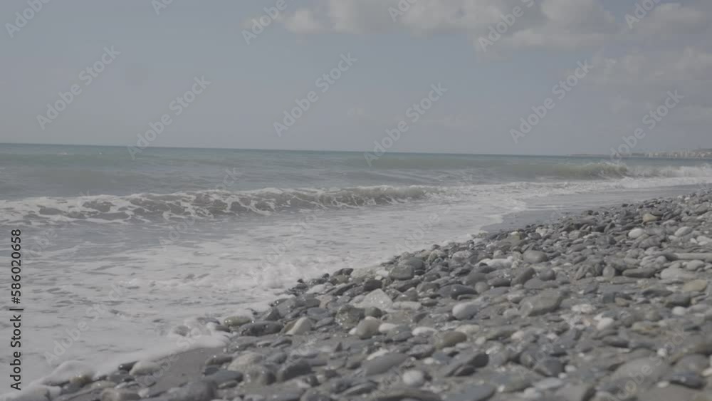 Waves hitting the beach full of stones on a sunny day in slowmotion LOG Waves hitting the beach full of stones on a sunny day in slowmotion LOG