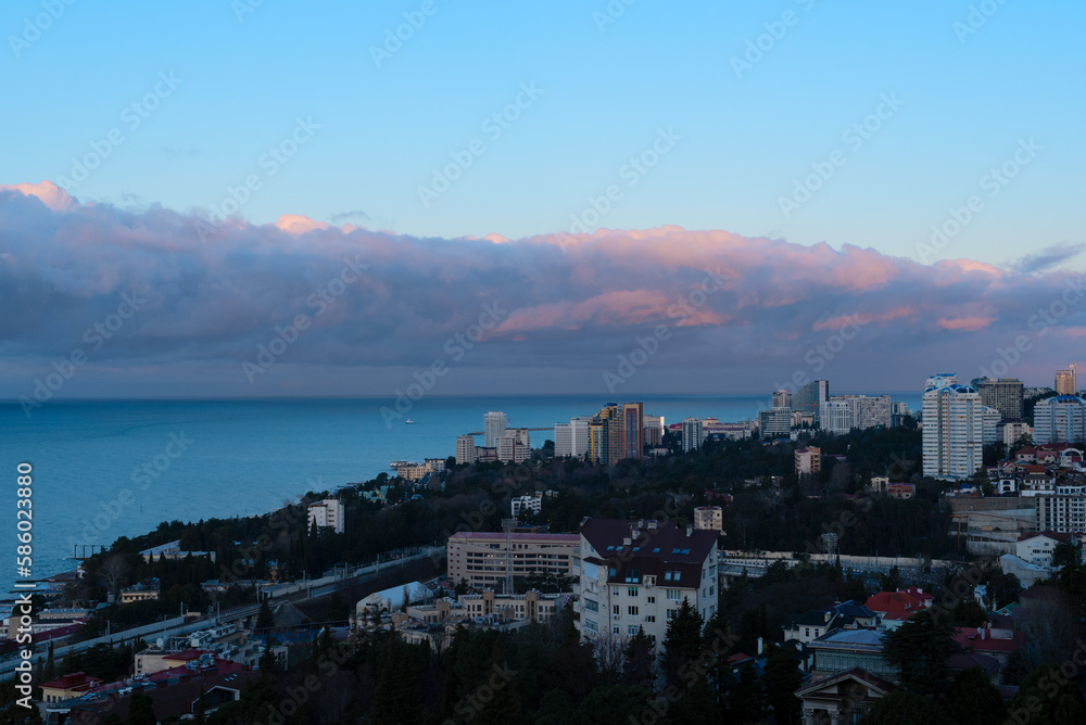 View of Sochi city on a sunny winter day with bright blue sky with white clouds and blue sea during beautiful sunrise. Nature background with selective focus. Travel concept