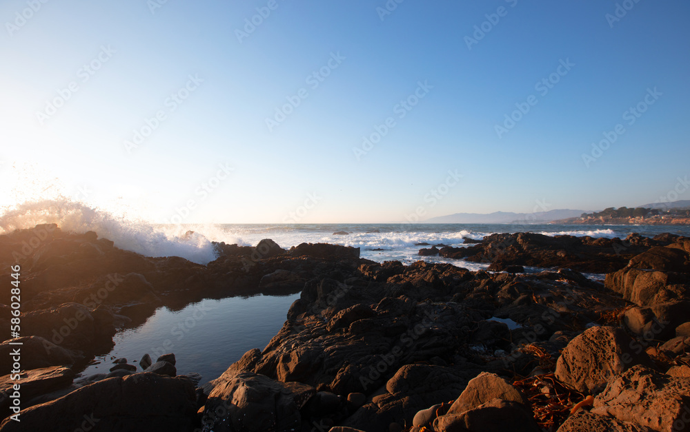 Obraz premium Wave crashing into rocky central California coastline during golden hour at Cambria California United States