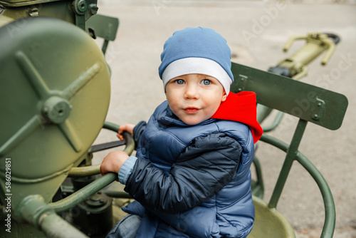 Little boys playing with historical world war tank. Portrait of young boy. Boy playing military tank. Low angle view of boy against clear sky. Children imagination and development. Kid playing wars