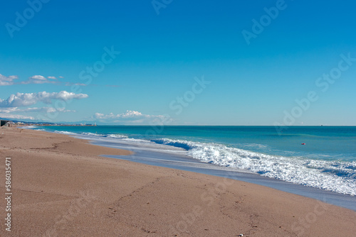 Small waves on sandy beach and blue sky no clouds in Manavgat Turkey