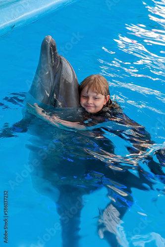 The small girl hugs a dolphin at the dolphin therapy session photo