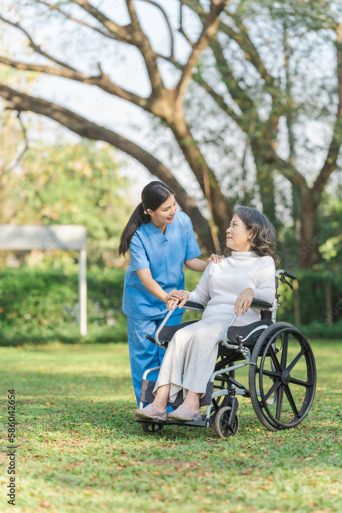 Young asian care helper with asia elderly woman on wheelchair relax together park outdoors to help and encourage and rest your mind with green nature. Young asian care helper with asia elderly woman on wheelchair relax together park outdoors to help and encourage and rest your mind with green nature.