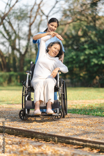 Young asian care helper with asia elderly woman on wheelchair relax together park outdoors to help and encourage and rest your mind with green nature. physical therapy © NanSan