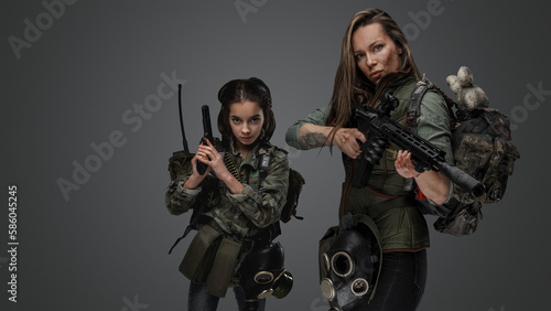 Portrait of woman and young girl survivors dressed in uniform and carrying backpacks.